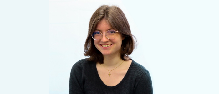 Head and shoulders image of a young woman wearing glasses and a black top