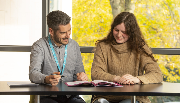 A student saw reviewing documents with a student adviser