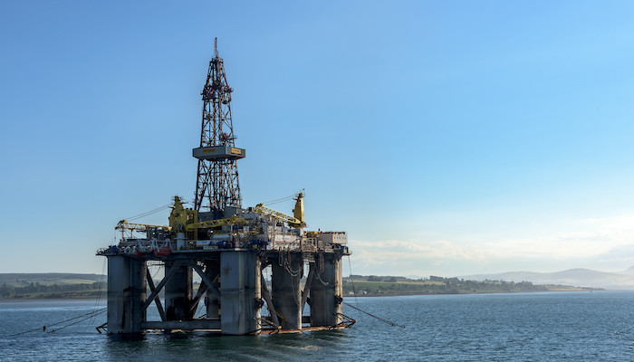 An oilrig platform standing in the sea with some land behind it Source: Mustang Joe, https://www.flickr.com/photos/mustangjoe/43258021631