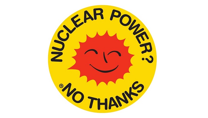 A yellow circle with a cartoon red sun in the middle with a smiley face. Around the ti op edeg is he text 'Nuclear Power?' and around the bottom 'No Thanks' all in black capital letters. Spouce: Anne Lund, https://commons.wikimedia.org/wiki/File:Smiling_Sun_English_Language.svg