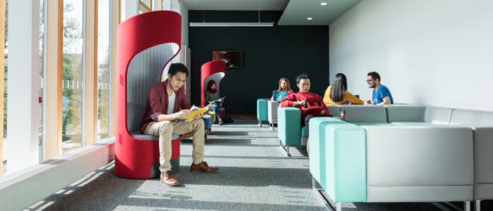 A modern building with brightly coloured soft chairs with people sitting and reading. Source: Glasgow University Image Library
