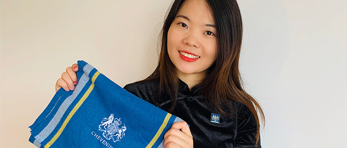 A young East Asian woman holding a banner for the Chevening Scholarships scheme