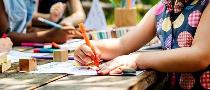View of a child's hand drawing a picture with other children behind them Source: RawPixel Publisher: IstockPhoto Link: https://www.istockphoto.com/photo/group-of-kindergarten-kids-friends-drawing-art-class-outdoors-gm671259542-122840763?clarity=false