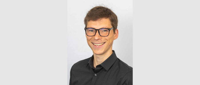 Young man with glasses smiling at the camera