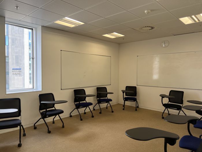 Flat floored teaching room with tablet chairs and whiteboards.