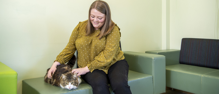 Woman in a waiting room stroking and holding a fluffy cat
