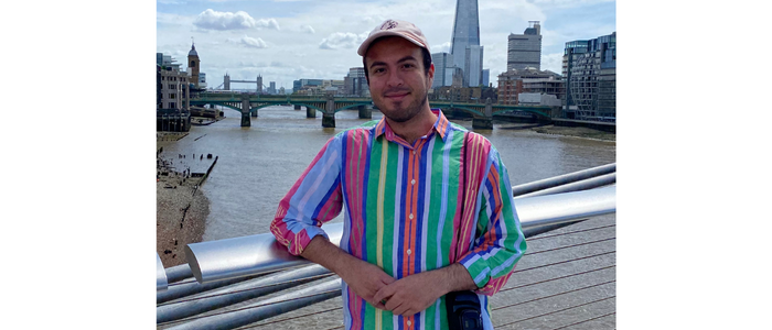 Male wearing a baseball cap and brightly coloured striped shirt smiles at the camera