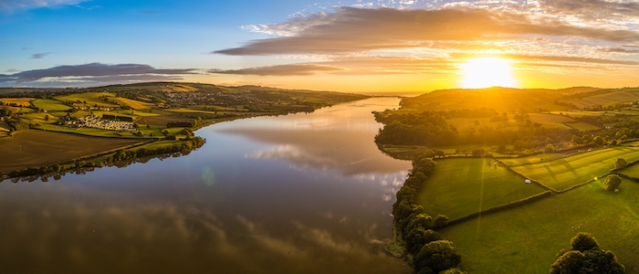 The sun rises over a river