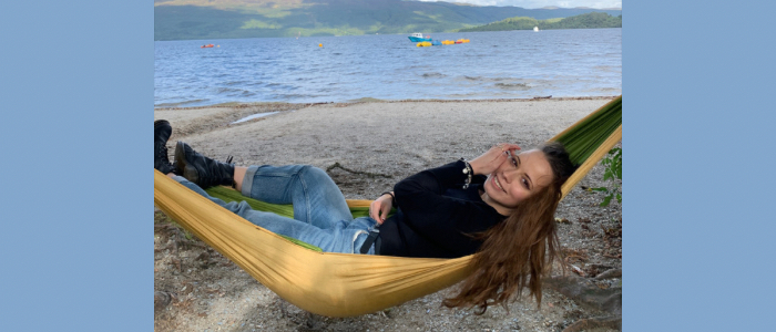 Young woman sitting in a hammock with Loch Lomond in the background 