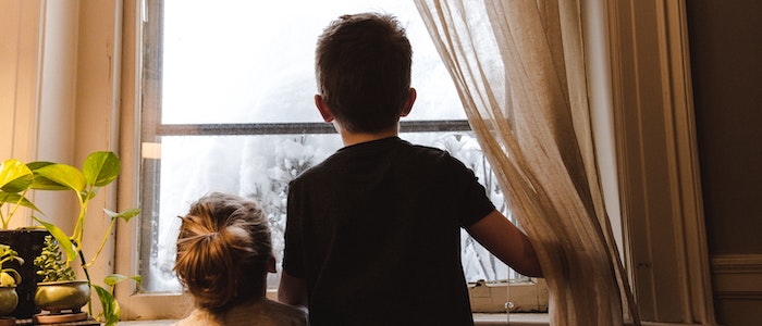 Silhouette of two children looking out of the window