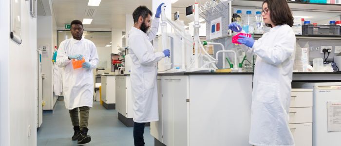 Three students working in a lab with various high-tech research equipment