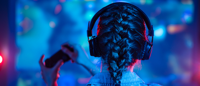 A picture of a woman using a video game controller in front of a computer monitor