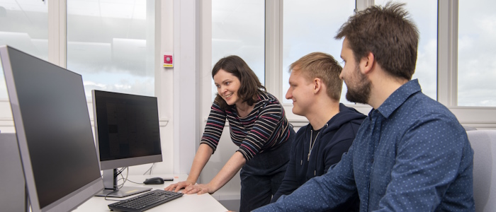 Three students looking at a monitor in computing class
