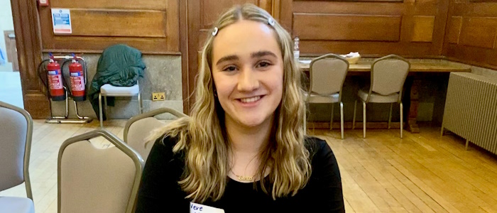 Student smiling with wavy, shoulder-length blonde hair and black top 