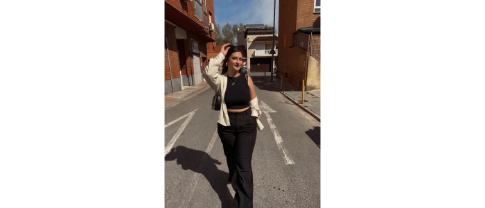 Female wearing black top and trousers and white cardigan standing on a road