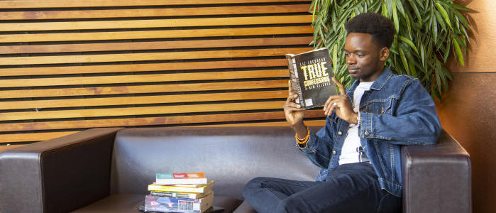 Someone sitting on a sofa reading a book